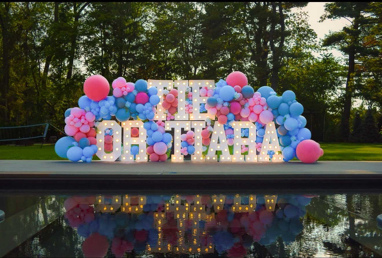 Tie or Tiara marquee letters with balloons reflected in a pool